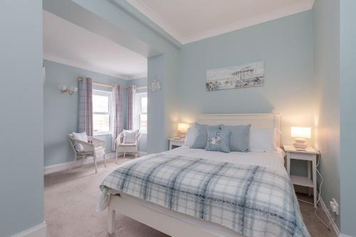 1 dormitorio con 1 cama blanca y paredes azules en The Knowe, en Portpatrick
