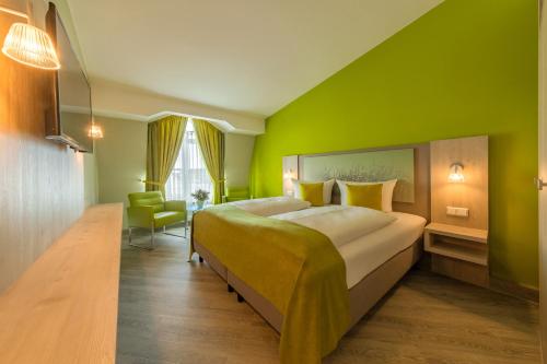 - une chambre avec un grand lit et un mur vert dans l'établissement Michels Inselhotel Vier Jahreszeiten, à Norderney