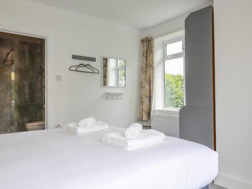 a white bedroom with a large bed with two towels at Pen-Y-Thon House in Newquay
