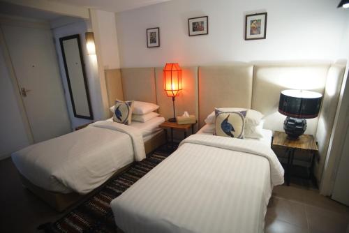 a hotel room with two beds and a lamp at Baan Suan Residence เฮือนพักบ้านสวน in Chiang Mai