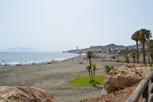 a beach with palm trees and people in the water at Irene Beach Málaga, Parking Gratuito in Cala del Moral