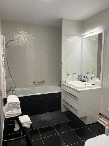 La salle de bains est pourvue d'une baignoire blanche, d'un lavabo et d'une baignoire. dans l'établissement Superbe studio Paris La Défense, à La Garenne-Colombes
