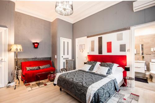 a bedroom with a red bed and a red couch at Hôtel de Charme Le Provence in Salon-de-Provence