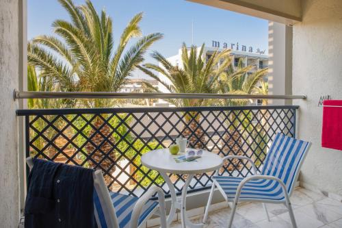 a table and chairs on a balcony with palm trees at Sol Marina Beach Crete in Gouves