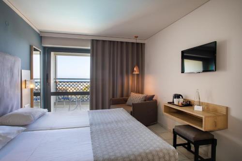 a hotel room with a bed and a desk and a balcony at Sol Marina Beach Crete in Gouves