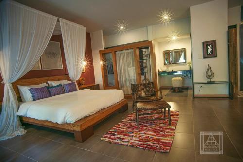 a bedroom with a large bed and a chair at Baan Suan Residence เฮือนพักบ้านสวน in Chiang Mai