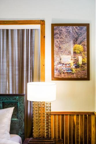 a lamp sitting next to a bed in a bedroom at Greens By Roomy, Kalam in Kalām