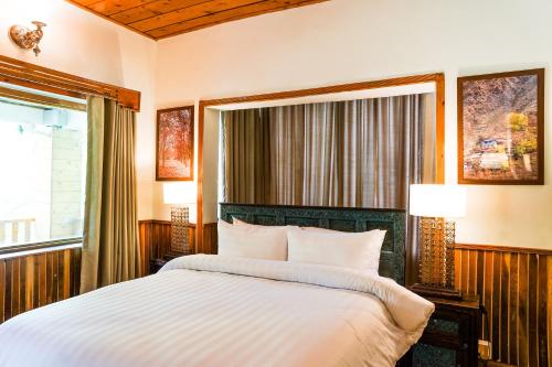 a bedroom with a large bed and a window at Greens By Roomy, Kalam in Kalām