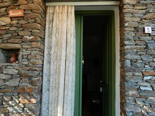 a door with a curtain next to a stone wall at Το Κατἑ in Artemonas