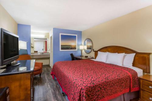 a hotel room with a bed, desk and television at Days Inn by Wyndham College Park Airport Best Road in Atlanta
