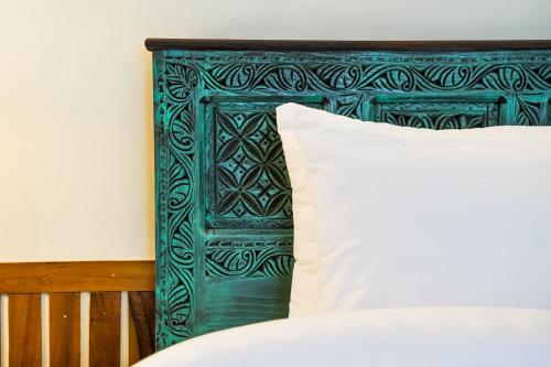 a bed with a green headboard with a white pillow at Greens By Roomy, Kalam in Kalām