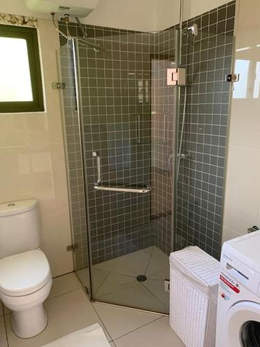 a bathroom with a toilet and a glass shower at Crystal Apartments Seychelles SeaView Upper Floor in Glacis