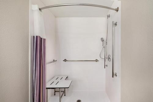 a bathroom with a shower and a bench in it at La Quinta Inn by Wyndham Columbus Airport Area in Columbus