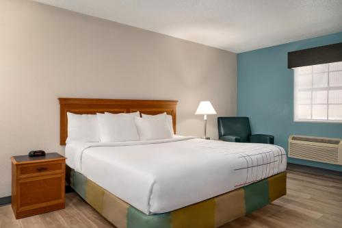 a bedroom with a large bed and a chair at La Quinta Inn by Wyndham Columbus Airport Area in Columbus