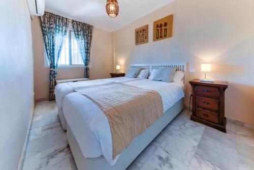 een slaapkamer met een groot bed en een houten nachtkastje bij Holidays2Cala del Moral & terraza & vista mar & piscina & parking in Cala del Moral