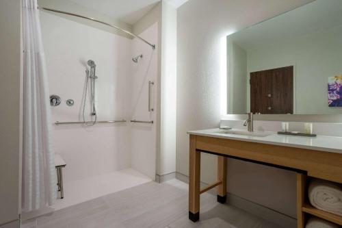 a bathroom with a sink and a shower with a mirror at La Quinta Inn & Suites by Wyndham Pflugerville in Pflugerville