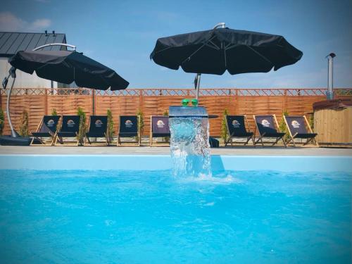 una fontana in una piscina con sedie e ombrelloni di Niko Jeziorsko 