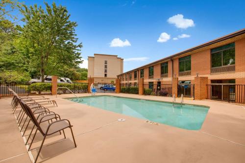 a swimming pool with chairs in front of a building at Clarion Pointe Atlanta Airport College Park in Atlanta