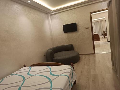 ein Schlafzimmer mit einem Bett, einem Stuhl und einem TV in der Unterkunft Aprt Hassan rba in Rabat