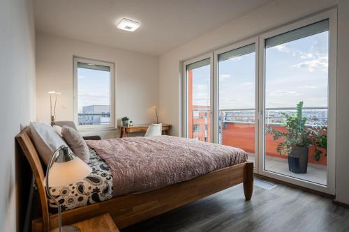 a bedroom with a bed and sliding glass doors at Penthouse Letňanské zahrady in Prague