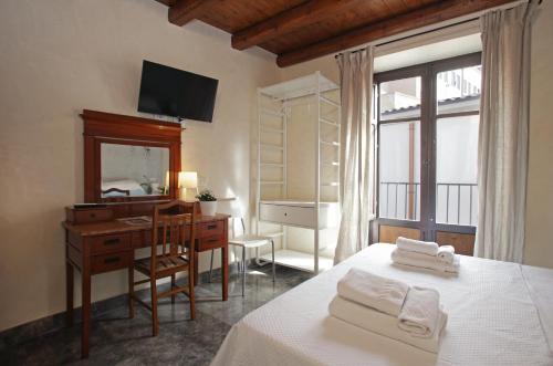 1 dormitorio con escritorio, 1 cama y espejo en Casa Miqvà - Rooms in shared apartment, en Palermo