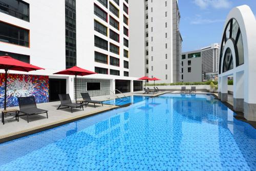 una piscina con sillas y sombrillas en un edificio en BelAire Bangkok Sukhumvit - SHA Extra Plus, en Bangkok