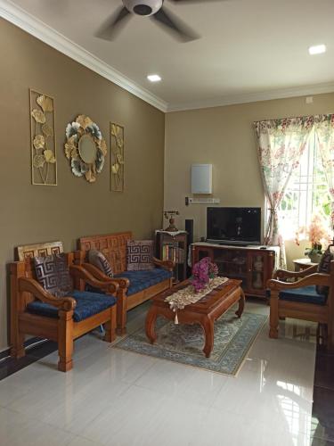 a living room with chairs and a table and a tv at Darney's Homestay Kg Bangau Tanjung in Temerloh