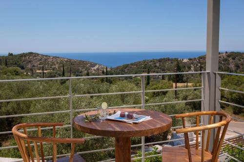 a table and two chairs on a balcony with a view at HYADES VILLAS LEFKADA in Agios Nikitas