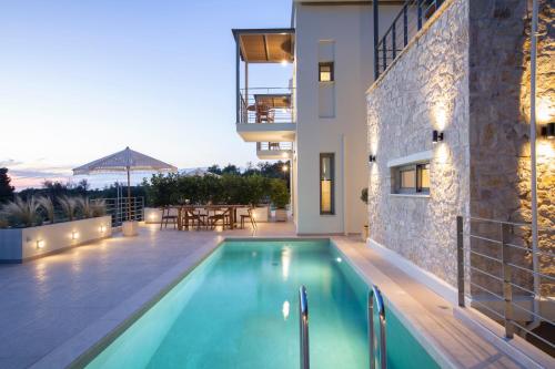 a villa with a swimming pool in front of a building at HYADES VILLAS LEFKADA in Agios Nikitas