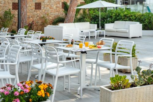 d'une terrasse avec des tables, des chaises et des fleurs blanches. dans l'établissement Hotel Vibra Marco Polo II - Adults only, à Sant Antoni de Portmany