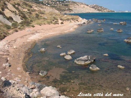 a group of rocks in the water on a beach at Appartamento Castel Sant'Angelo in Licata