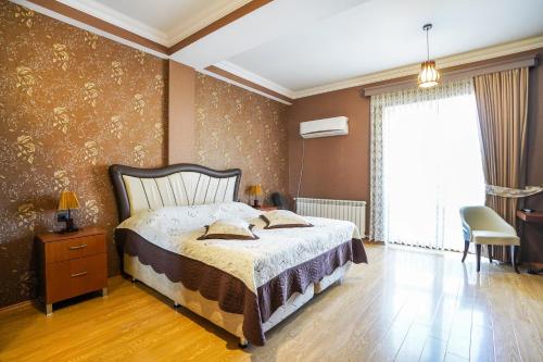 a bedroom with a bed and a chair and a window at Natali Hotel in Borjomi