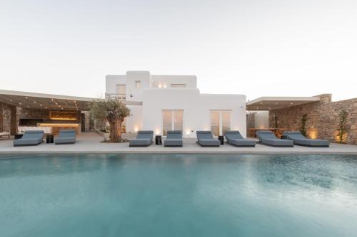 una piscina con sedie a sdraio e un edificio di Blue Eye Grand Villa Mykonos a Kalafatis