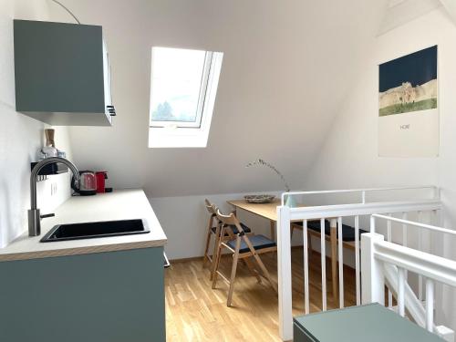 a small kitchen with a sink and a table at Bright + Cozy Dachgeschoß Maisonette im Zentrum in Bregenz