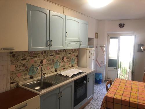 a kitchen with white cabinets and a sink and a table at Casa di NELLA in Campiglia Marittima