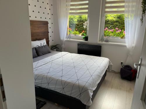 a bedroom with a bed with white sheets and two windows at Apartmán Laza in Donovaly