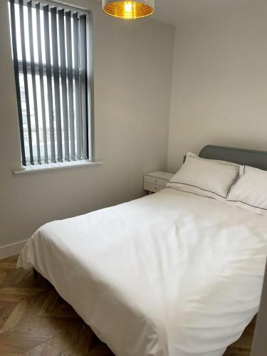 a white bed in a room with a window at Smith Stayz Apartments in Blackpool