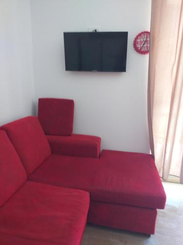 a living room with a red couch and a flat screen tv at Caulonia mare in Caulonia Marina