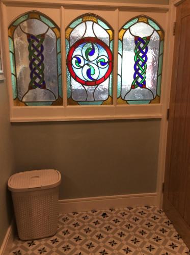three stained glass windows in a room with a trash can at Quayside luxury apt Roundstoneselfcatering in Roundstone