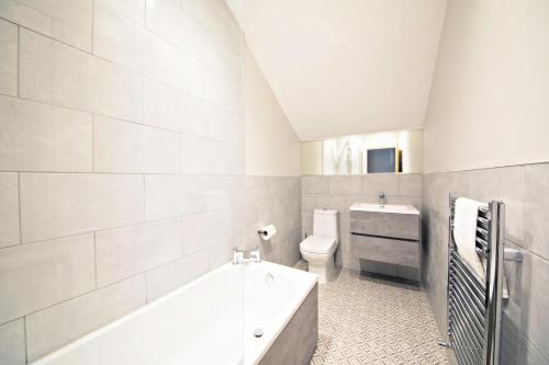 a white bathroom with a tub and a toilet at The Loft Apartment, 8 Granville Road in Harrogate