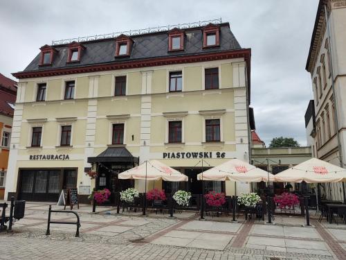 a building with tables and umbrellas in front of it at Piastowski26 in Jelenia Góra