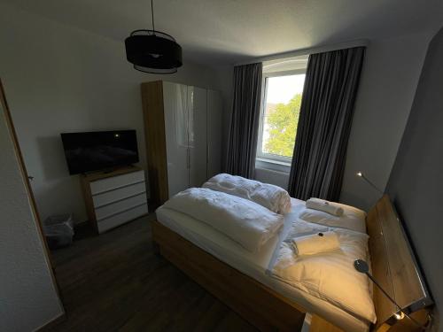 Hotel Sonnenschein nähe Messe und Flughafen في دوسلدورف: غرفة نوم بسرير وتلفزيون ونافذة