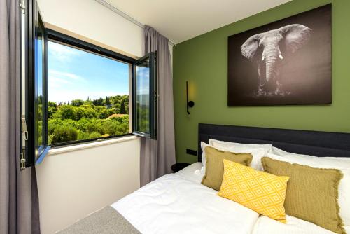 Un dormitorio con una cama y una ventana con una foto de elefante en Villa Barović, en Mlini