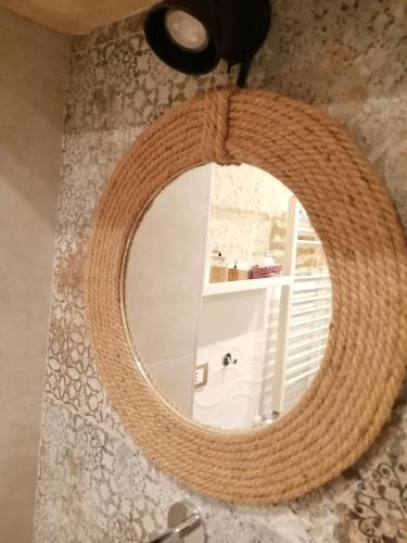 a bathroom mirror with a large wicker ring around it at Palazzo Emy in Lecce