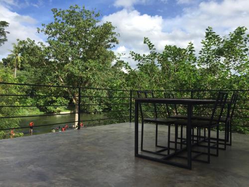 a table and chairs on a patio with trees at ชลลดา ริเวอร์ โฮมสเตย์ แก่งกระจาน in Ban Wang Malako