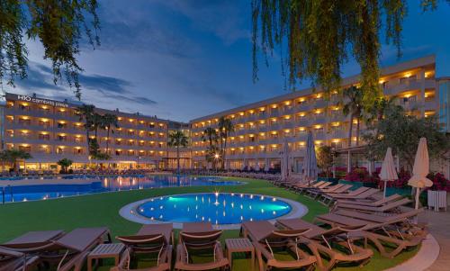 una vista exterior de un hotel con tumbonas y una piscina en H10 Cambrils Playa, en Cambrils