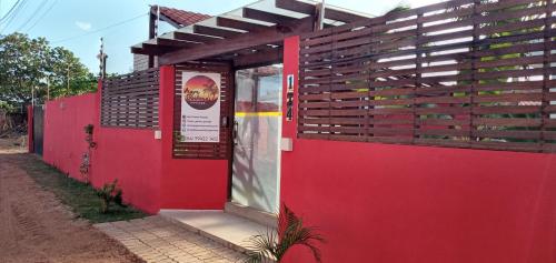 Czerwona ściana z czerwonymi drzwiami i napisem w obiekcie AYRE GOSTOSO POUSADA w mieście São Miguel do Gostoso