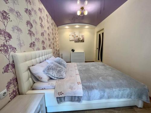 een slaapkamer met een wit bed met paarse muren bij 2-комн ЛЮКС в центре Вишенки in Vinnytsya
