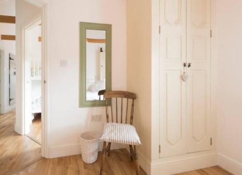 a wooden chair in a room with a mirror at Beautiful barn with private log fired hot tub in Maidstone