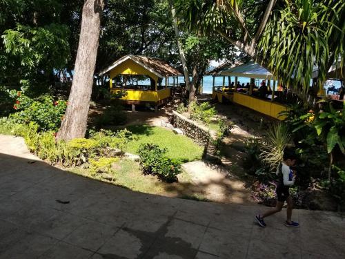 a young boy walking down a sidewalk next to a train yard at Don Arc White Beach Resort in Initao